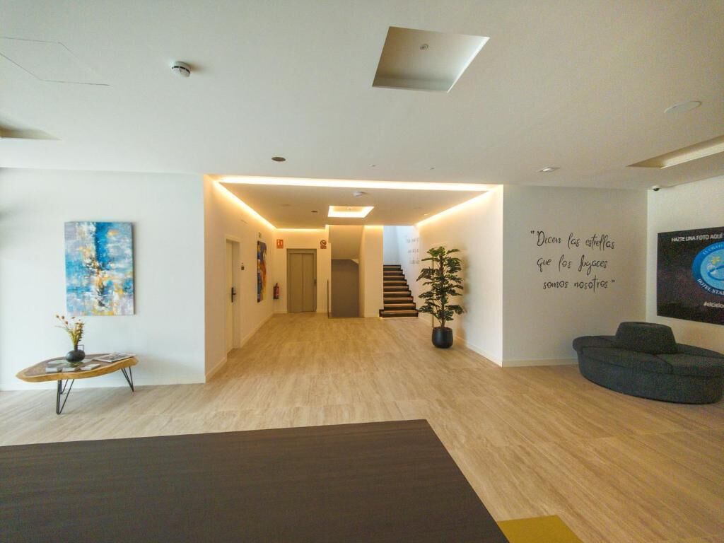 Un interior moderno con piso de madera, una escalera, un sofá oscuro y una pared con una cita.