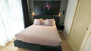 Un dormitorio moderno con una cama grande, un televisor de pared y una obra de arte con vista a la ciudad.