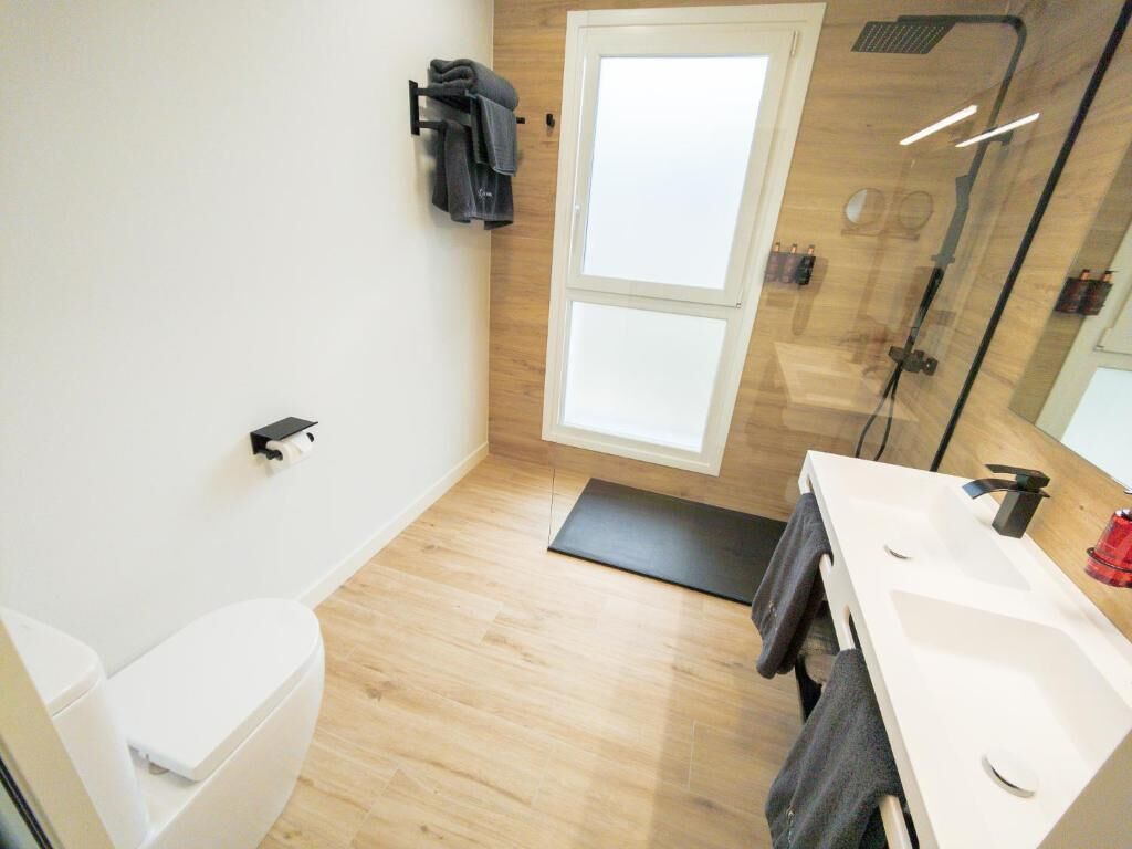 A modern bathroom with a toilet, shower, and sink.