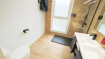 A modern bathroom with a toilet, shower, and sink.