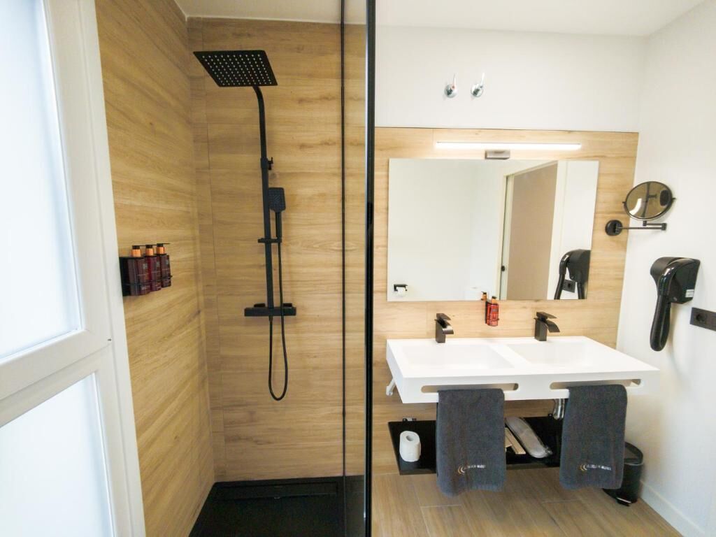 Un baño moderno con ducha, lavabo, espejo y teléfono.