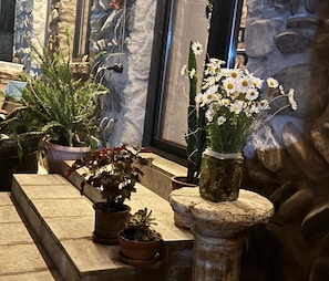A stone ledge with potted plants and a vase of white flowers.