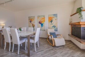 Ein Essbereich mit einem weißen Tisch und Stühlen, einer Holzbank und einem Kamin.