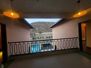 A balcony with a pool, a view of a hilly landscape, and two hanging pendant lights. - Retreat at 3BHK Pool farmhouse near Ghrishneshwar Temple/Ajanta Ellora with AC (Chhatrapati sambhajinagar)