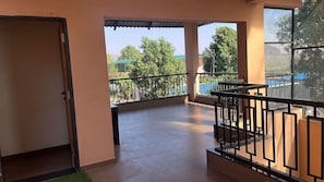 A balcony with a view of trees and a building in the distance. - Retreat at 3BHK Pool farmhouse near Ghrishneshwar Temple/Ajanta Ellora with AC (Chhatrapati sambhajinagar)