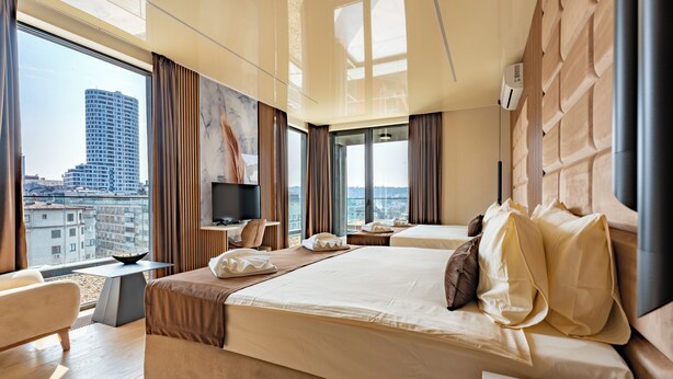 Camera d'hotel con un letto grande, televisione, una scrivania e vista sulla città.