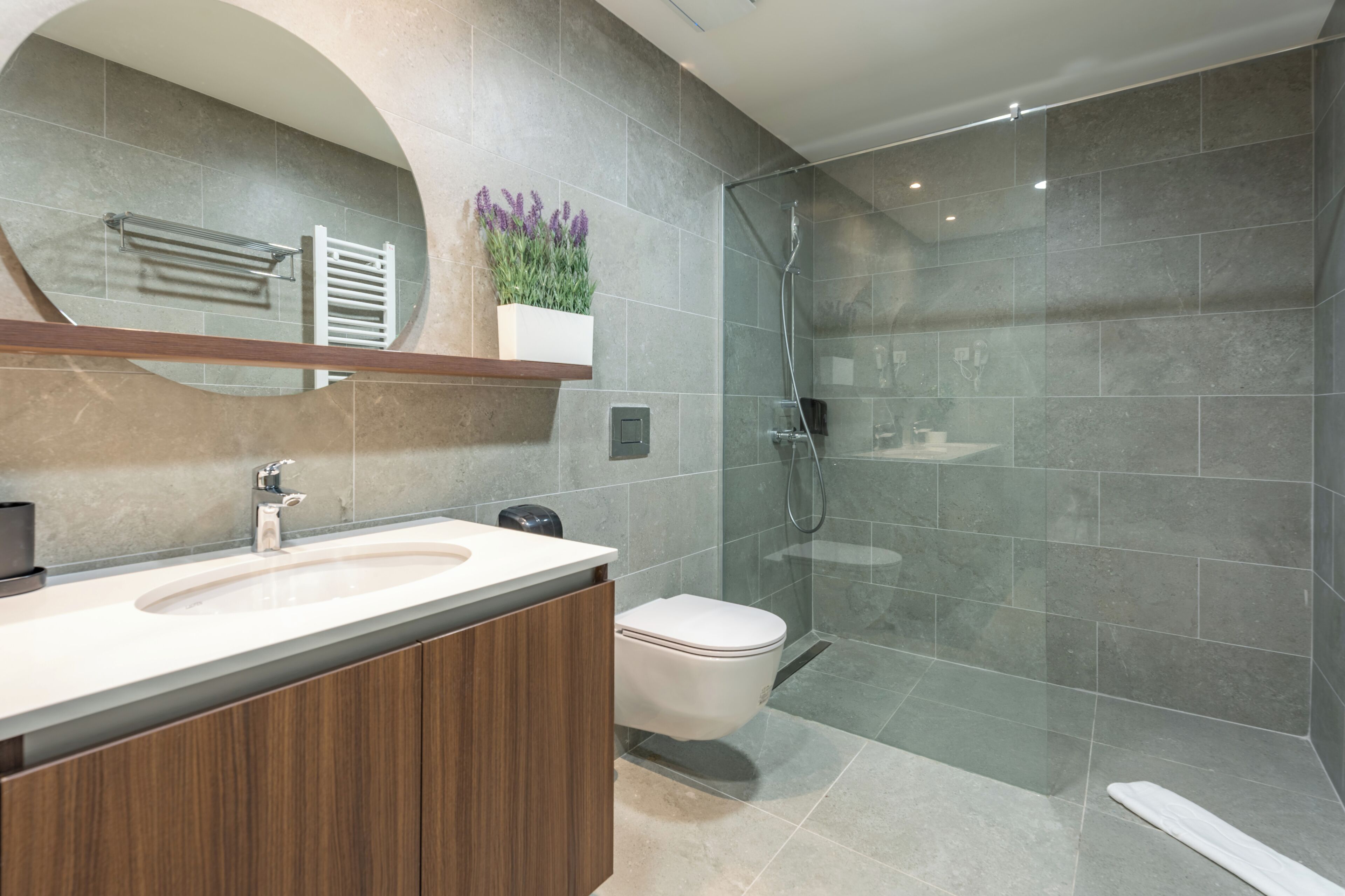 A modern bathroom with a glass shower enclosure, a built-in sink, and a toilet.