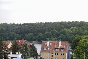 A building with a red-tiled roof, a visible car service sign, and a forested hill in the background. - Domki Całoroczne Jaga (Olsztyn)
