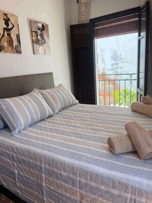 A bed with striped bedding, a headboard, and a view of a balcony with a railing.