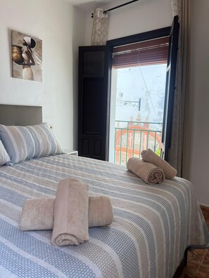 Quarto com cama, almofadas, janela com vista e porta.