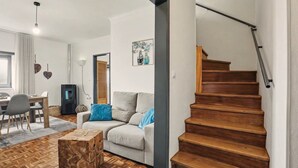 A living room with a sofa, a coffee table, a staircase, and a dining area. - Cantinho do Préstimo (Préstimo)
