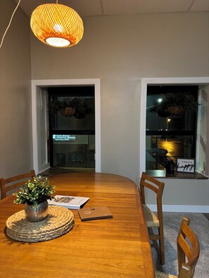 A dining table with chairs, a woven placemat, a laptop, and a potted plant. - Brand X Loft Spacious 2 Bedroom Loft in the Heart of Hebron (Hebron)
