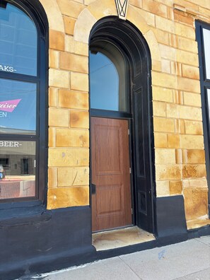 A building with a brick facade, a wooden door, and a window with a reflection.