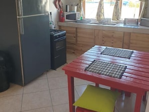 Cozinha equipada com geladeira, fogão, micro-ondas e armários de madeira.