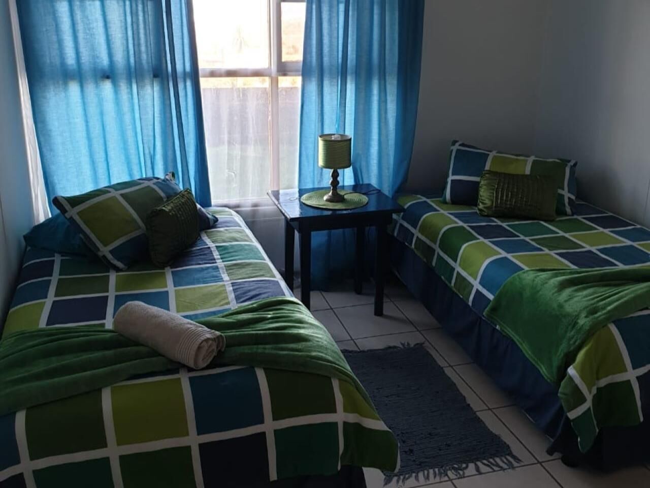 Een kamer met twee bedden, een tafeltje en een lamp.