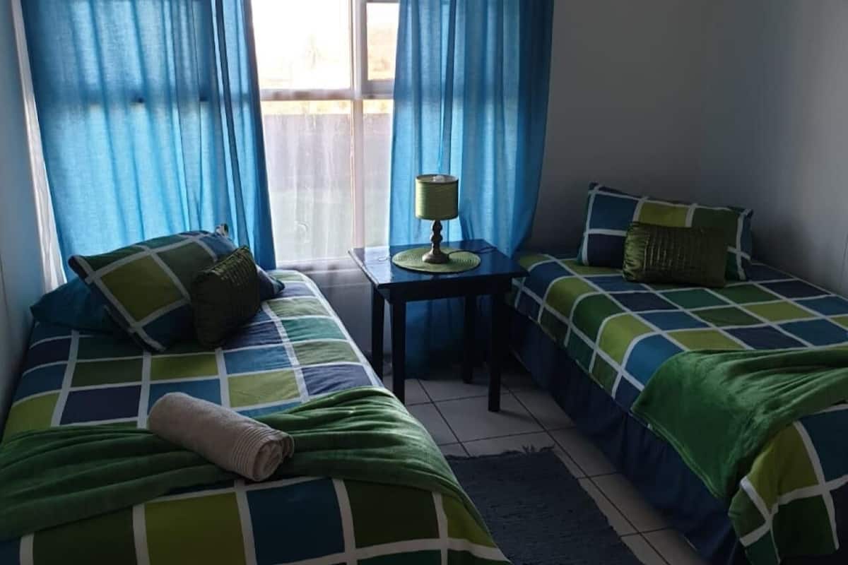 Una habitación con dos camas, una mesita y una lámpara.