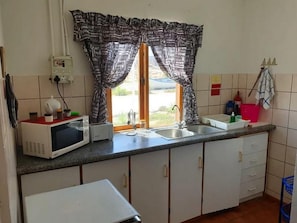Una cocina equipada con microondas, tostadora, lavaplatos y armarios.