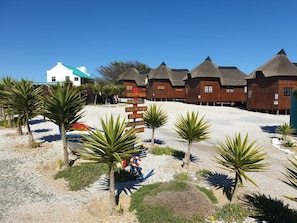 Een resort met gebouwen met rieten daken, palmbomen en een bord met pijlen.