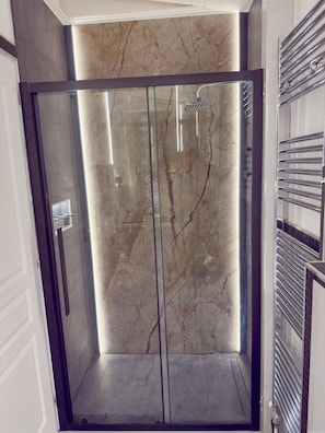 A modern bathroom with a glass-enclosed shower, marble walls, and a chrome towel rack. - Apartment Vagia Nea Smyrni (Nea Smirni)