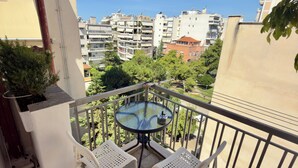 Ein Balkon mit rundem Tisch und zwei Stühlen, mit Blick auf ein Wohngebiet mit mehreren Gebäuden.