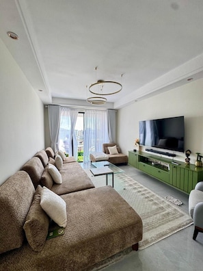 Una sala de estar moderna con un sofá modular, un televisor de pantalla plana y un mueble de entretenimiento verde.