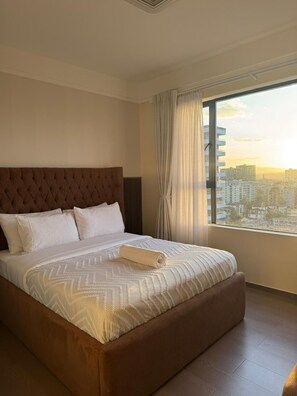 Una habitación de hotel con una cama grande, vistas a la ciudad y una ventana con cortinas.