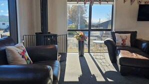 Ein Wohnzimmer mit Kamin, zwei Ledersofas, einem Couchtisch und einem großen Fenster mit Aussicht.