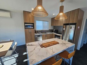 Una cucina moderna con mobili in legno, un'isola in marmo e illuminazione a sospensione.