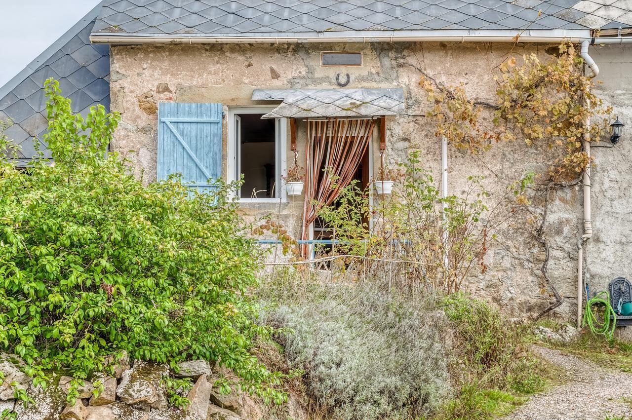 A rustic stone house with a window, a door, and a small garden area.
