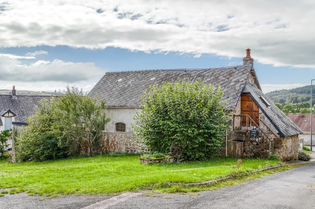 A rustic stone building with a steeply pitched roof, a wooden door, and a small porch.