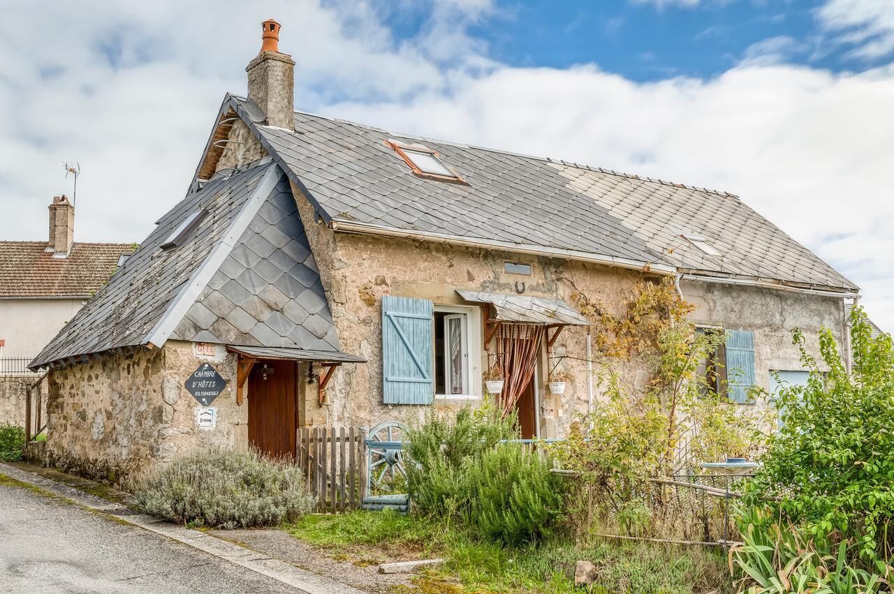 A rustic stone building with a sloped roof, a wooden door, and a small window with shutters.