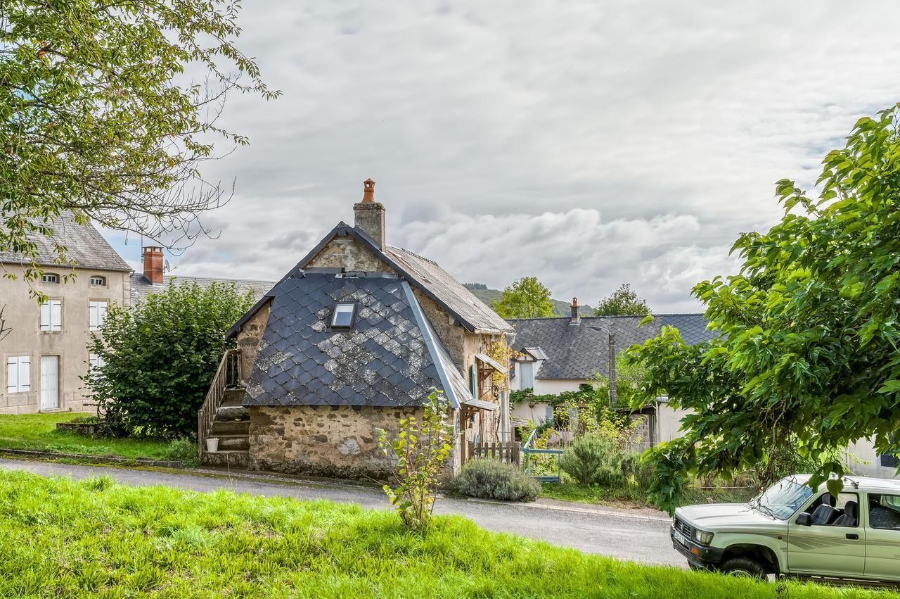Une maison en pierre avec un toit en pente, une cheminée et une petite fenêtre.