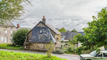 Une maison en pierre avec un toit en pente, une cheminée et une petite fenêtre.
