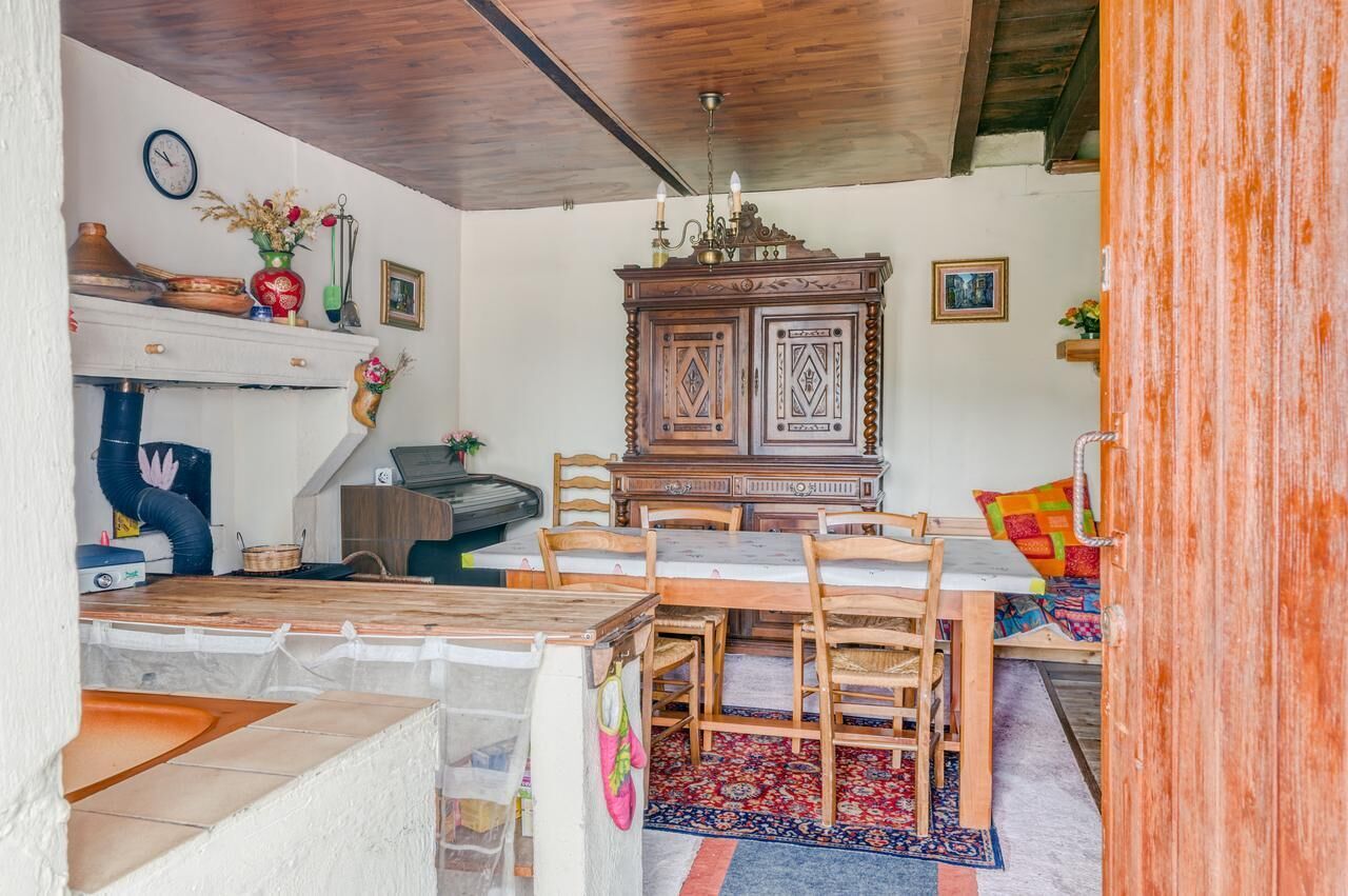 Un comedor con una mesa y sillas de madera, un aparador con objetos decorativos y un reloj en la pared.