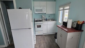 A kitchen with a refrigerator, stove, microwave, and sink. - Cozy 2-bedroom cottage in marvelous Ludington with AC (Ludington)