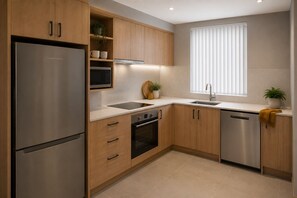 Eine moderne Küche mit Holzausstattung, Edelstahlgeräten und einem Fenster mit Jalousien.