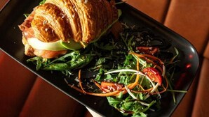 Ein Teller mit einem Croissant-Sandwich und einem Salat.