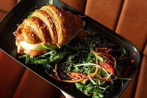 Ein Teller mit einem Croissant-Sandwich und einem Salat.