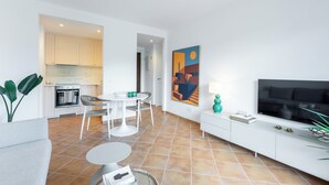 Un soggiorno moderno con televisore, zona pranzo e cucina sullo sfondo.