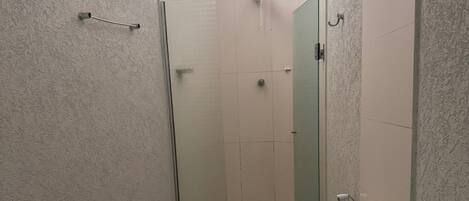 Un baño pequeño con inodoro, cabina de ducha y dispensador de papel higiénico.