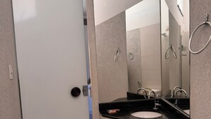 A bathroom with a glass door, a black sink, a mirror, and a shower area. - ITER HOTEL  (Rifaina)