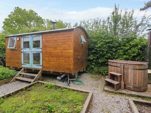 Eine Holzhütte mit Tür, Fenstern und einer kleinen Rampe zu einem Kiesplatz.