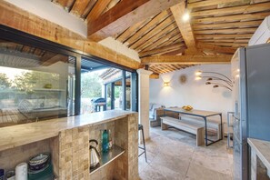 Eine moderne Küche mit Holzboden, einem integrierten Kühlschrank und einem Essbereich mit einer Bank.