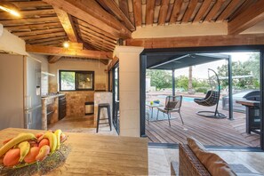 Eine Küche mit Steinrückwand, Holzbalkendecke und einem Essbereich mit Blick auf einen Pool.