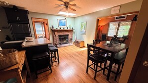 A kitchen with a fireplace, wooden flooring, and a ceiling fan.