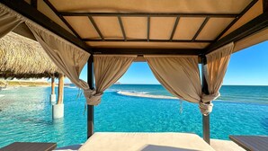 Ein Zimmer direkt am Strand mit einem Bett, zwei Tischen und Meerblick.