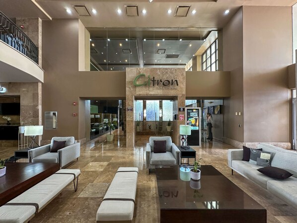 Eine großzügige Lobby mit einer zentralen Sitzecke, einem sichtbaren Restaurant namens 'Citrón Fine Cuisine' und einem modernen Design mit hoher Decke und großen Fenstern.