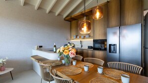 Une cuisine moderne dotée de meubles en bois, d’appareils électroménagers en acier inoxydable et d’un îlot central avec des sièges.