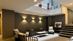 Un soggiorno moderno con soffitto alto, una scala e un lucernario.