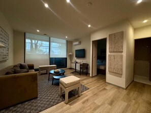 Ein modernes Wohnzimmer mit einer Couch, einem kleinen Tisch, einem Fernseher und einer Projektionsleinwand.